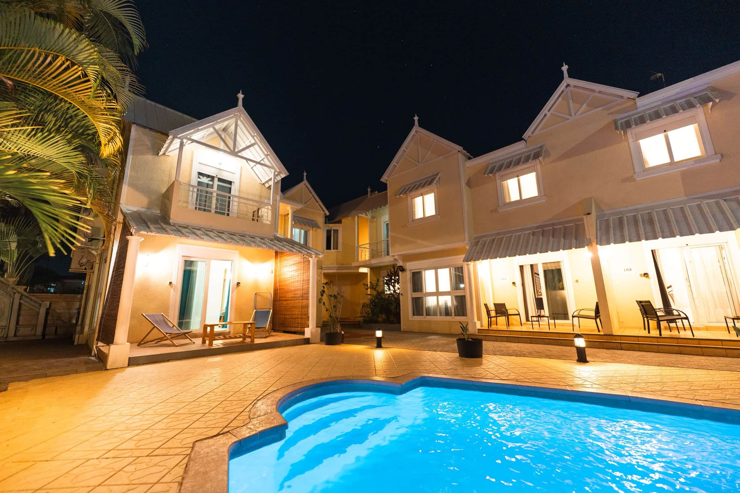 Lit villas around a pool at night in Flic en Flac